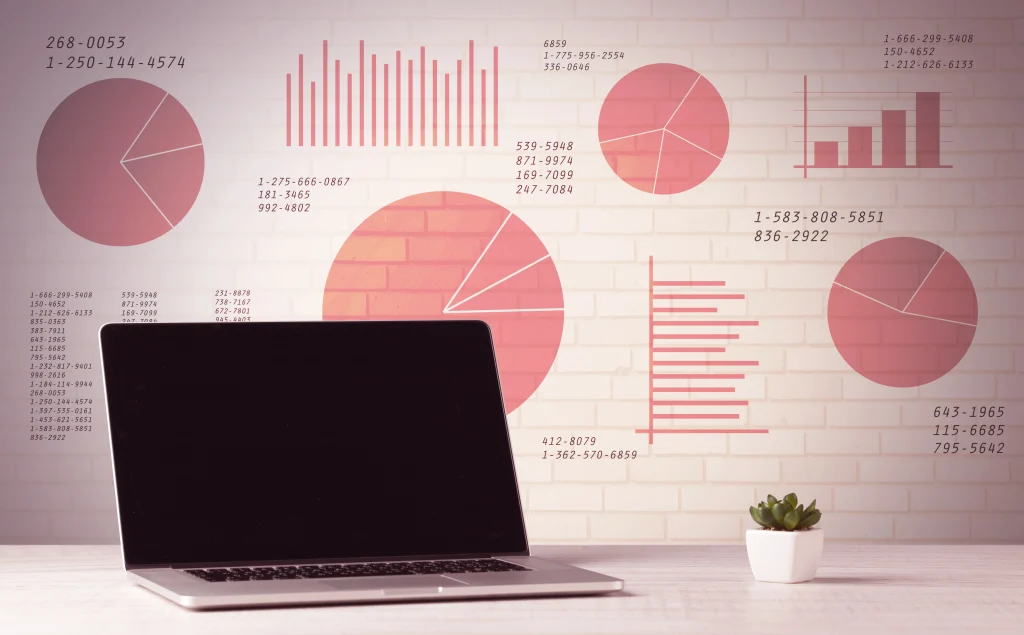 Portátil en una oficina con gráficos de datos en la pared